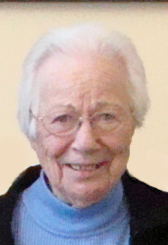 A headshot of Claribel giving a wide smile. She is wearing a blue turtleneck.