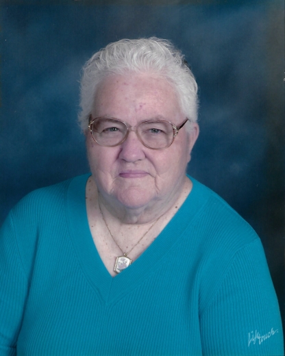 A professional portrait of Beatrice. She wears a blue shirt in front of a blue background and thinly framed glasses.