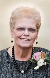 Judy smiles, wearing wire-rimmed glasses and a flower corsage.