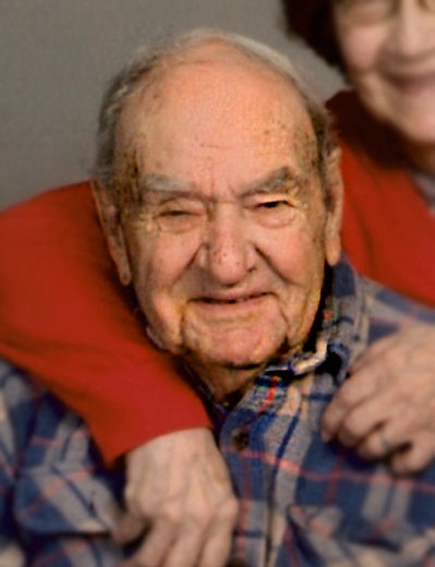 Carl beams at the camera. Joan is cut out of the photo, but her arms are wrapped around his neck lovingly.